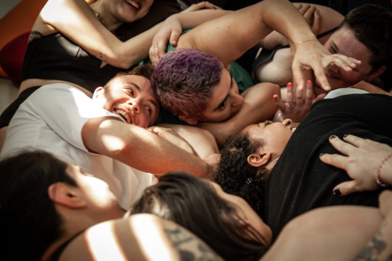 A bunch of queer people in a cuddle pile in the sun