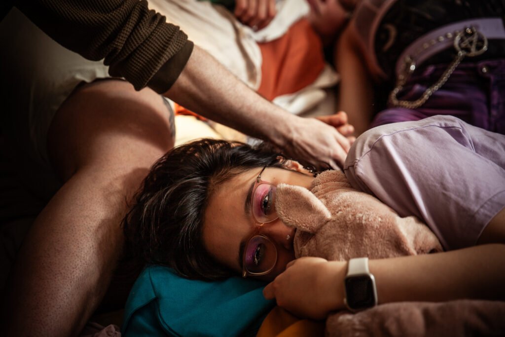 Person resting with teddy bear and glasses.
