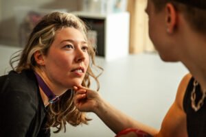 Person touching chin of seated woman.