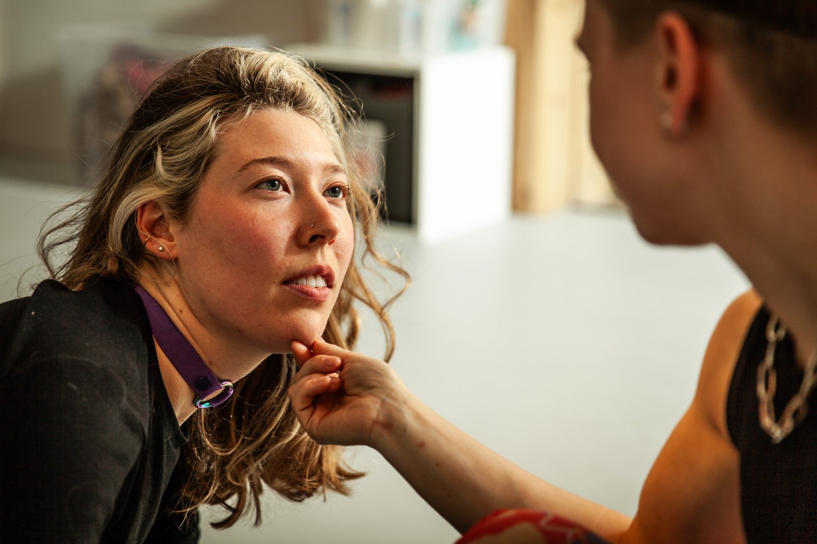 Person touching chin of seated woman.