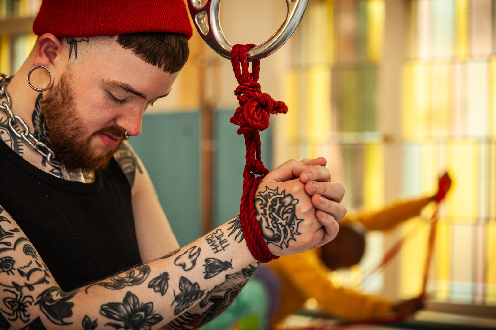 A cute tattoeed guy has his wrists bound to a ring