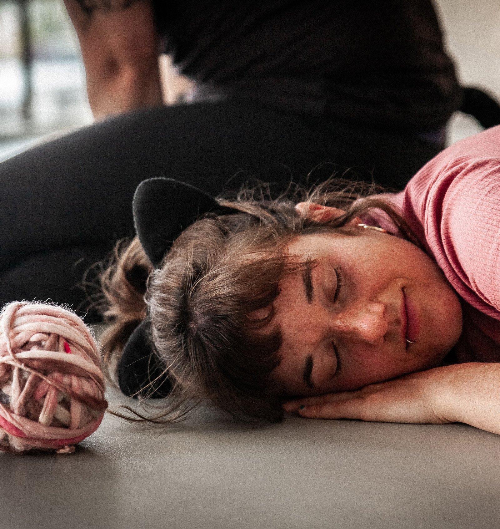 Person wearing cat ears rests with ball of yarn beside them