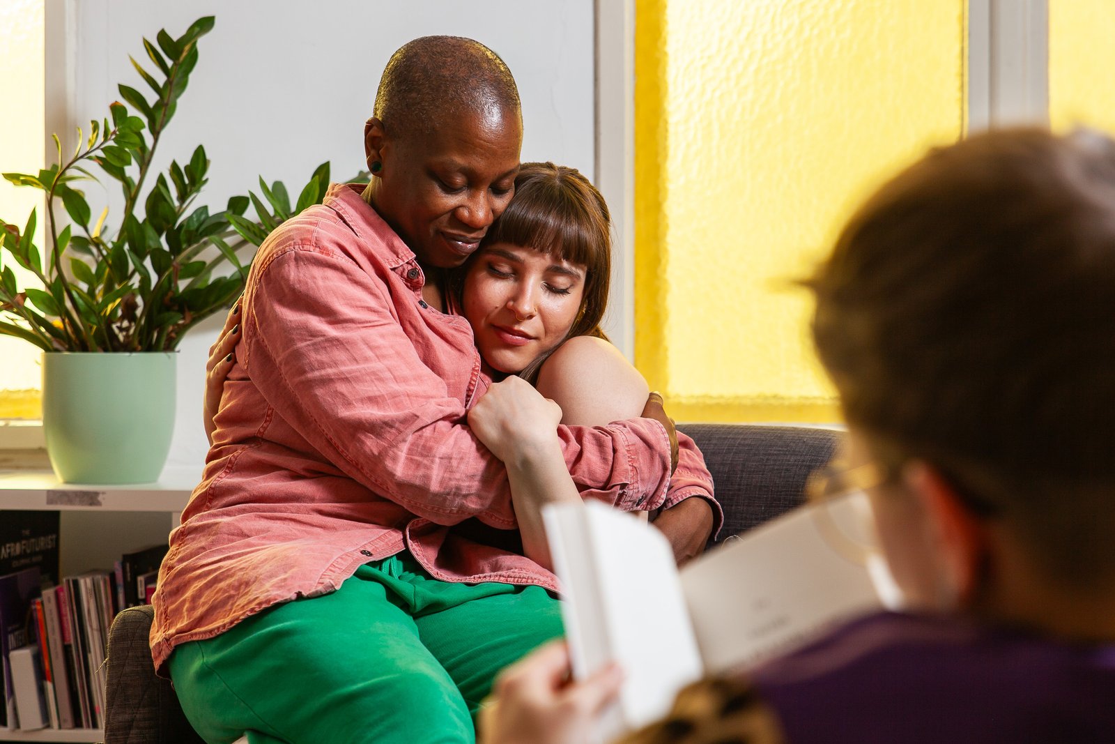 Two people hugging on a couch, reading nearby.