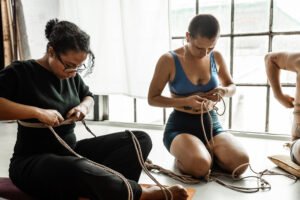 Two people practicing rope tying indoors.