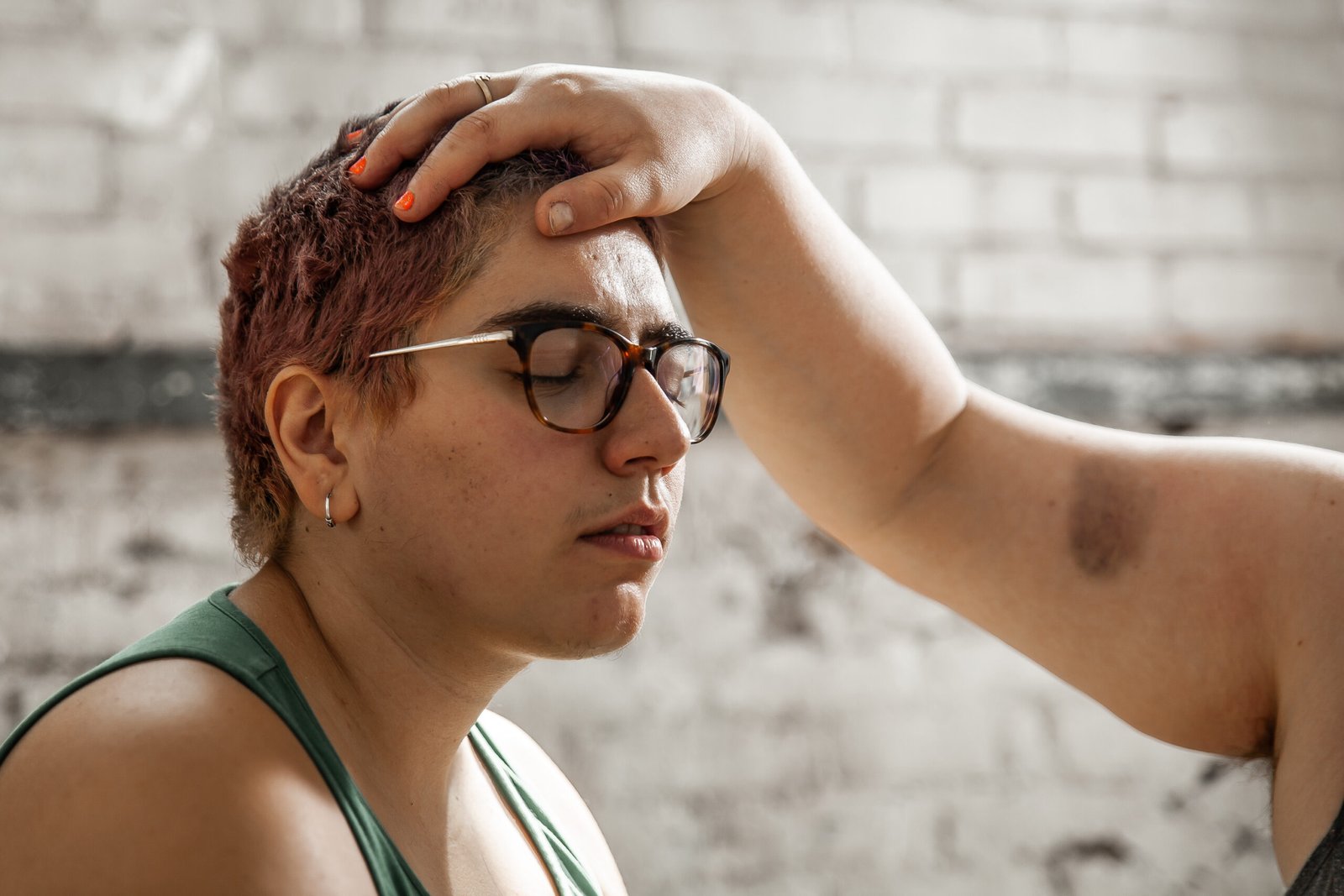 Person meditating with another's hand on their head.