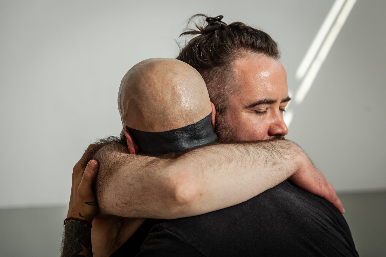 Two men hugging warmly, eyes closed.