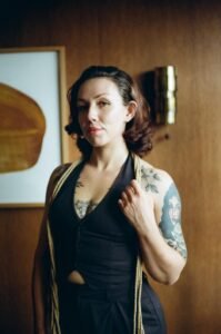 Person with tattoos holding a rope indoors.