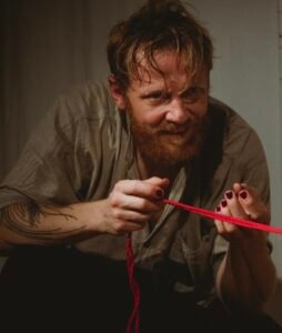 Person holding red rope with intense expression.