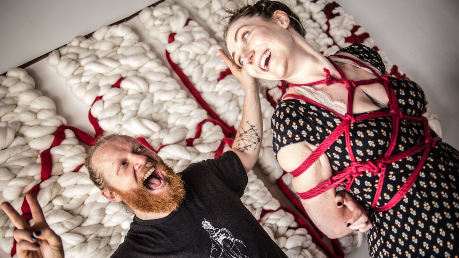 Smiling couple posing in creative yarn art installation.