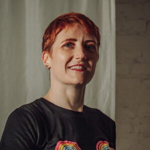 Smiling person with short red hair indoors
