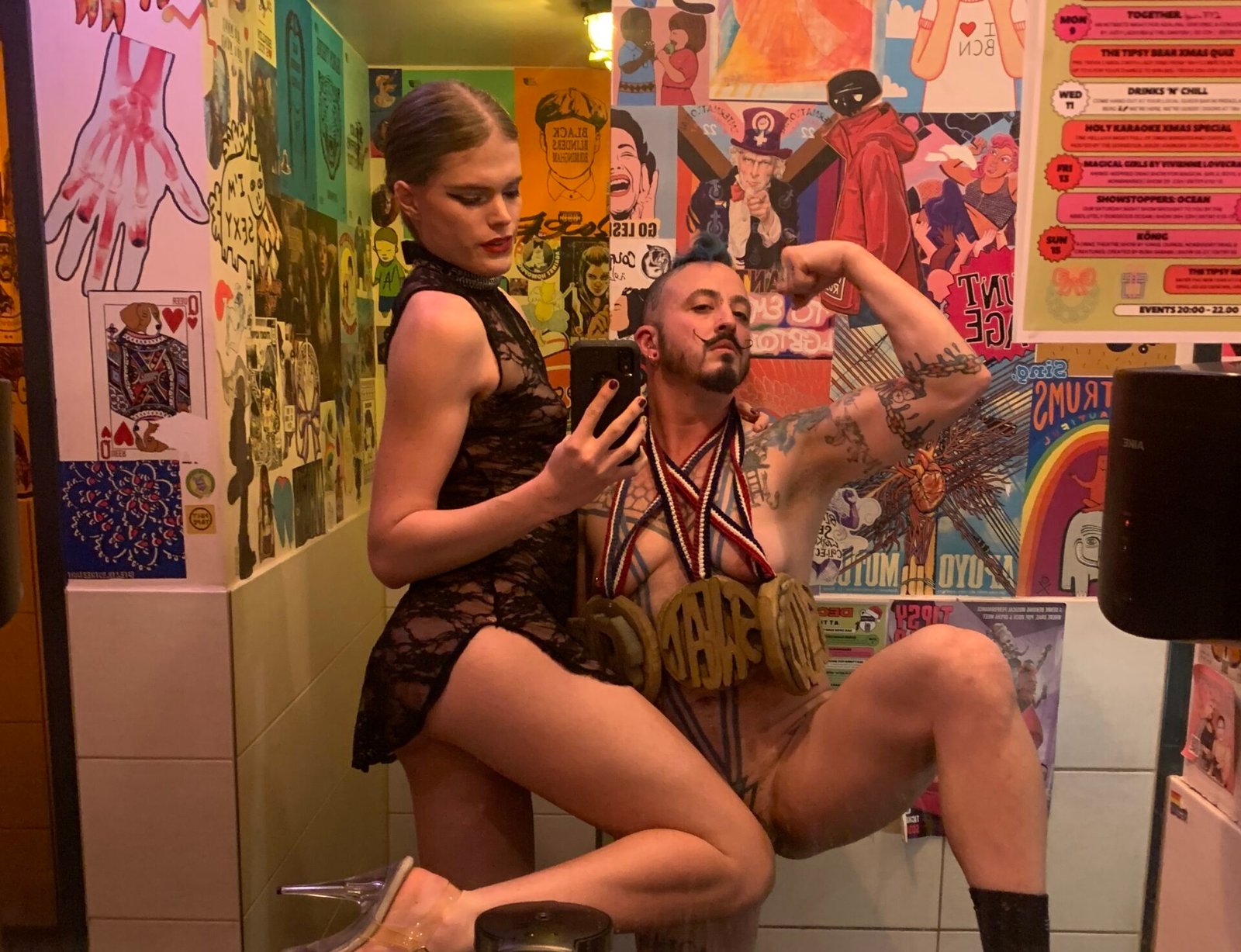 Two people posing in colorful, decorated bathroom.
