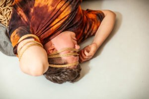Person lying bound with rope on floor