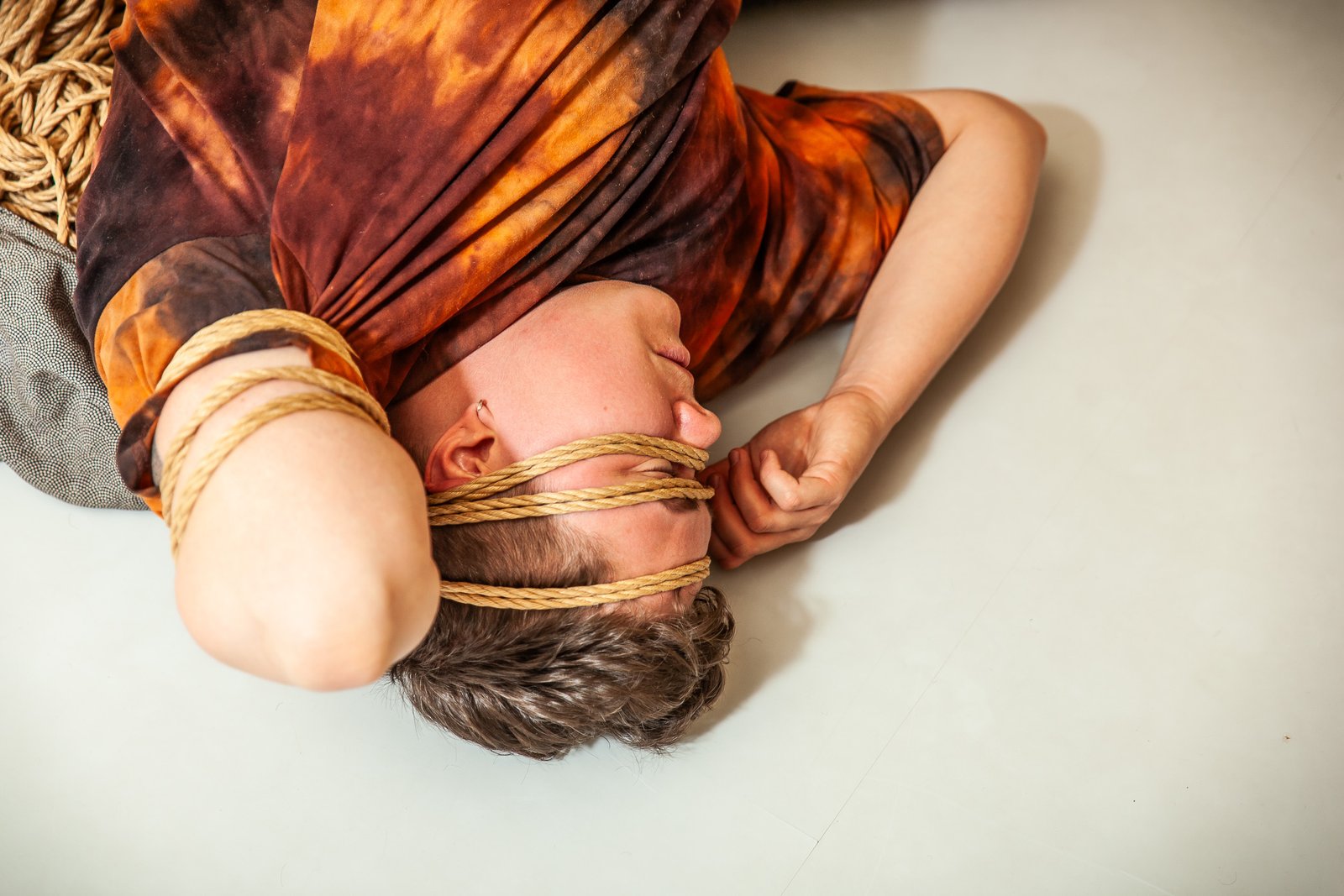 Person lying bound with rope on floor