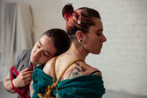 Two people embracing with decorative ropes and tattoos.