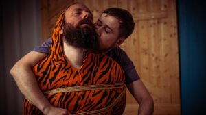 Person in orange tiger suit tied with rope.