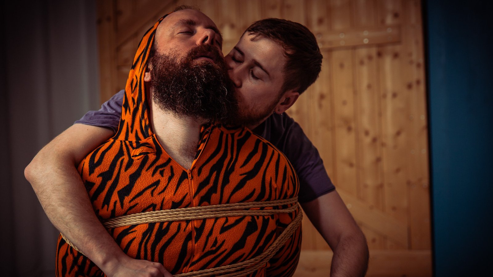 Person in orange tiger suit tied with rope.