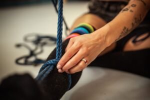 Close-up of person tying a blue rope.