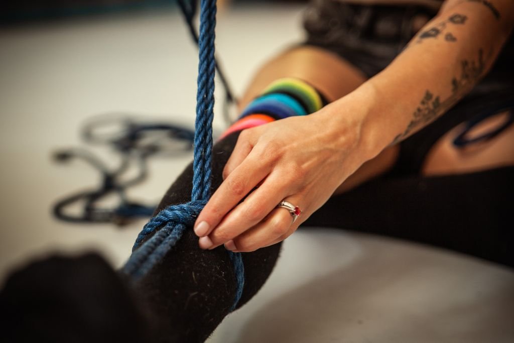 Close-up of person tying a blue rope.