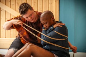 Two people engaged in rope art activity indoors.