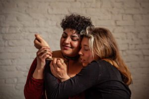 Two people embracing with gentle expressions and a rope.