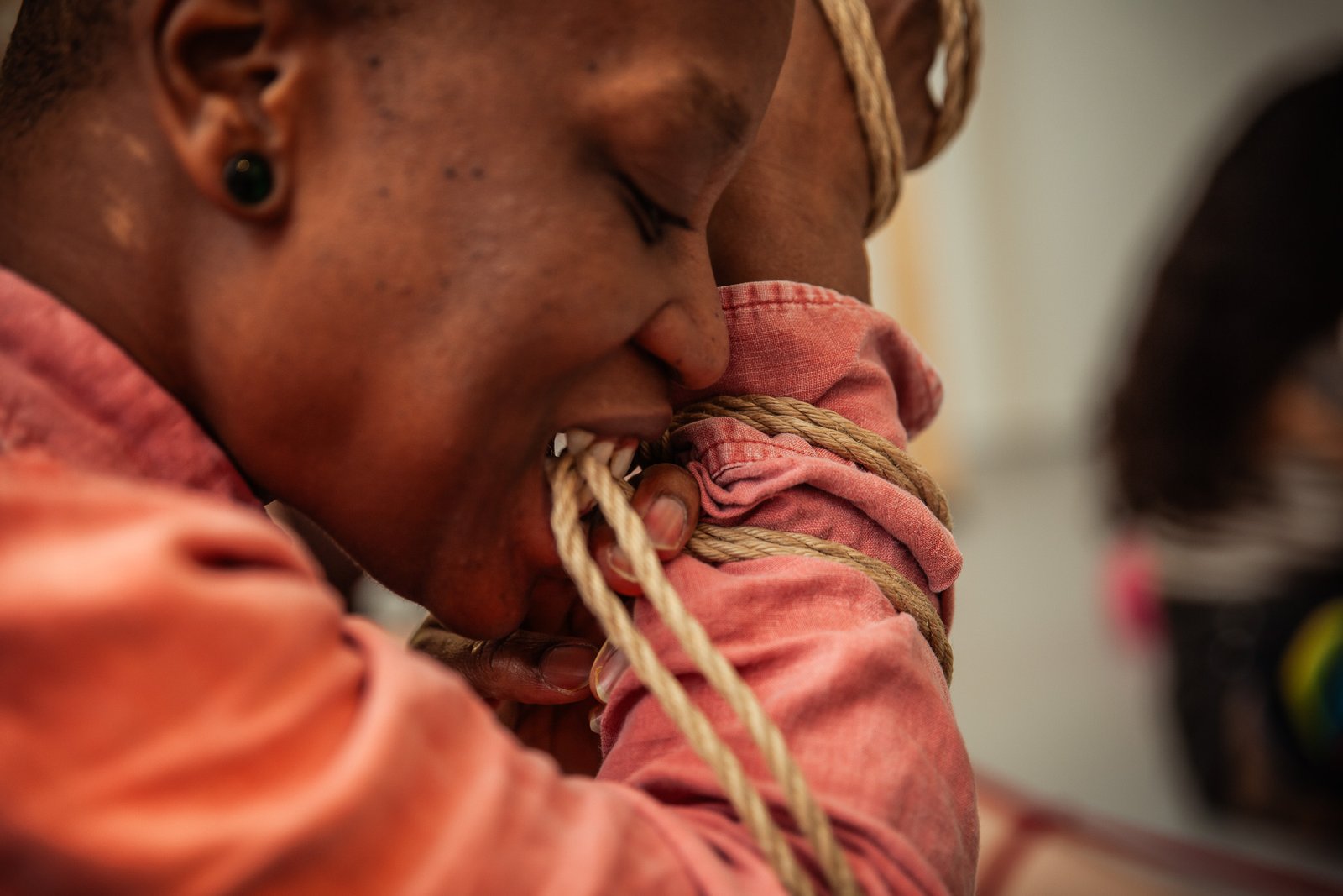 Person biting ropes wrapped around arm.