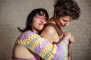 Two people hugging with rope and crochet sweater.