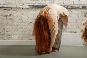 Person bending over, touching toes on gray floor.