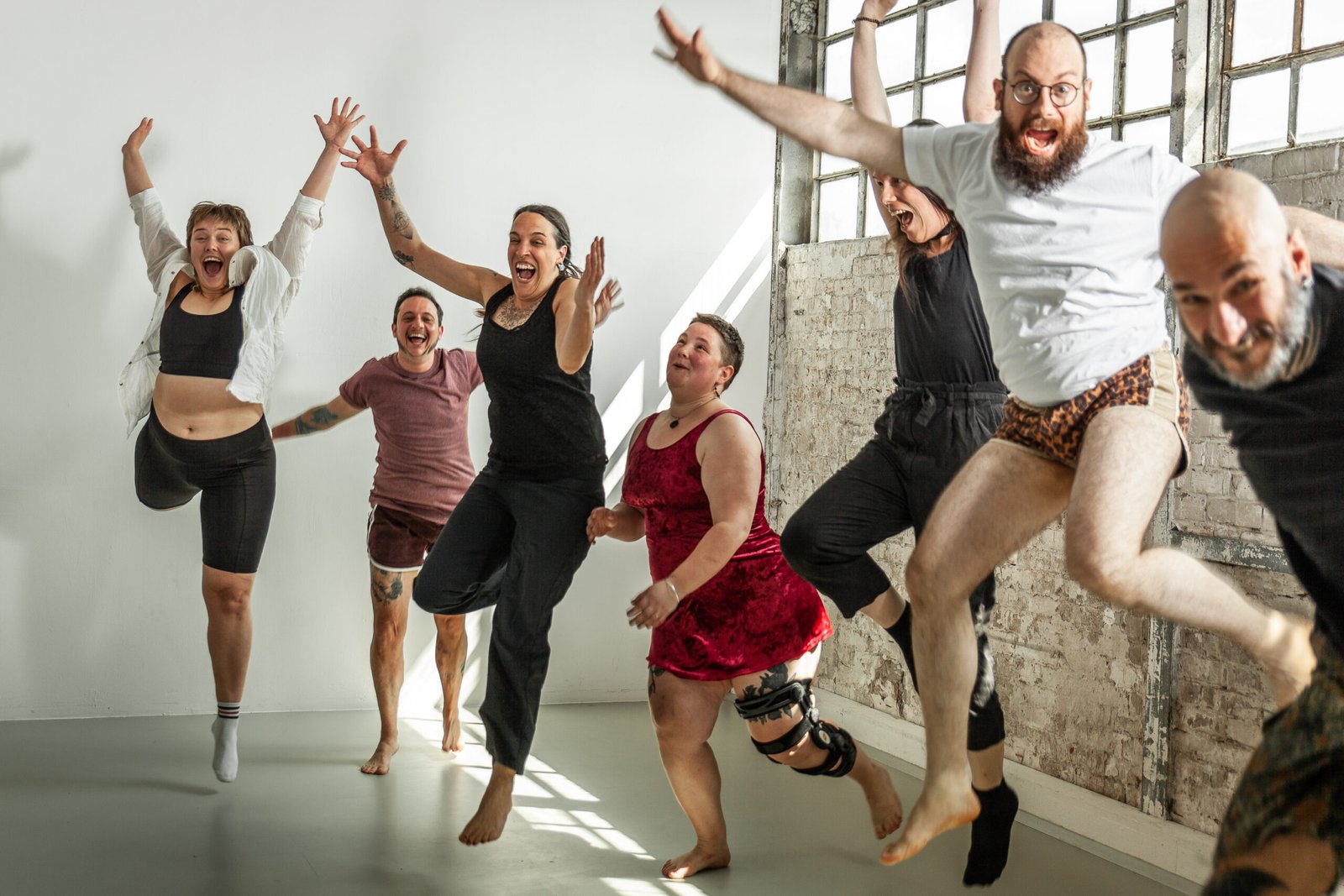 Diverse group joyfully jumping indoors.