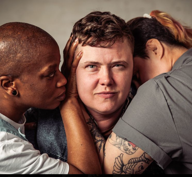 Three people embracing closely in conversation