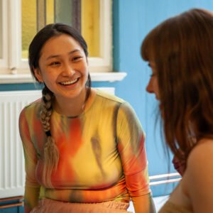 Two women smiling and talking indoors.