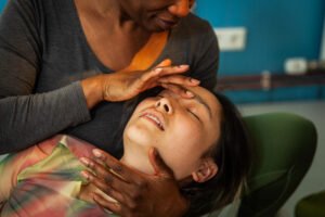 Therapist performing facial massage on woman.