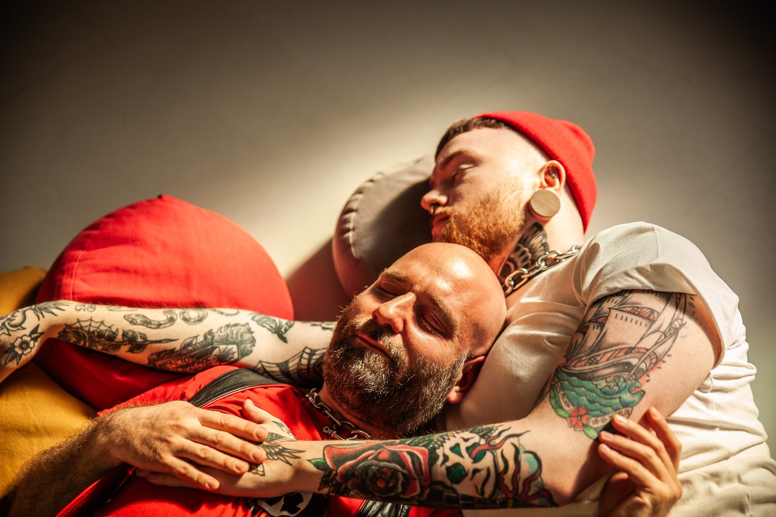 Tattooed couple cuddling on colorful pillows