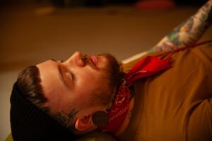 Person resting with tattoos and red bandana