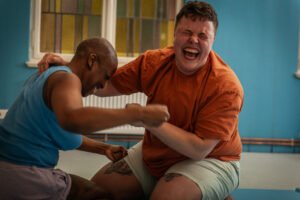 Two people playfully wrestling and laughing.