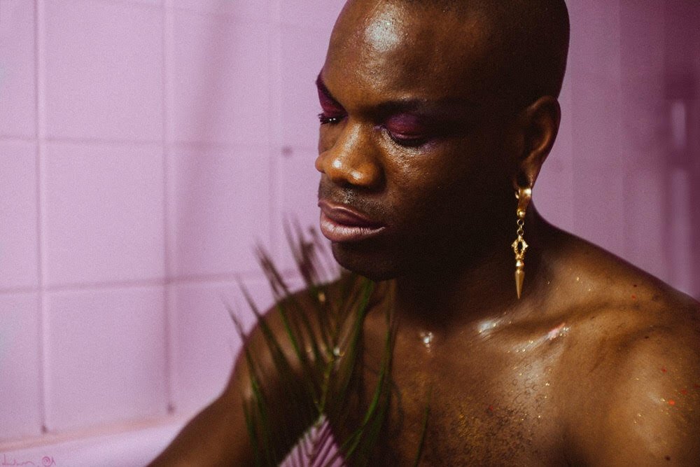 Person with makeup and earrings in pink setting.