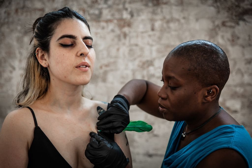 Tattoo artist inking client's shoulder