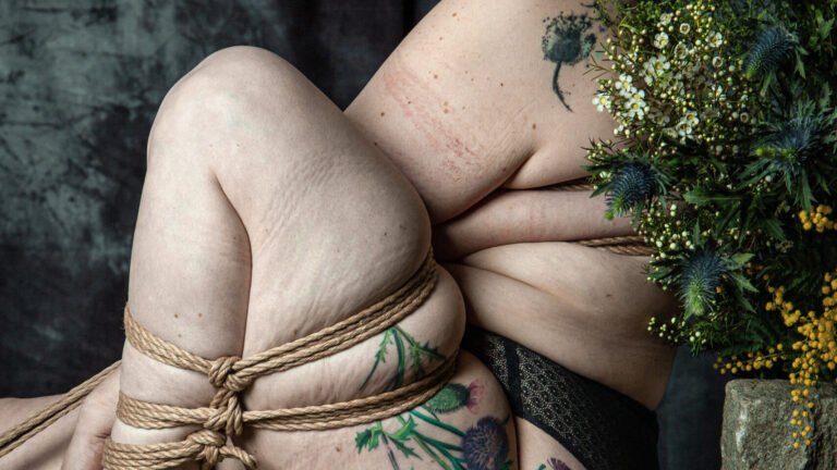 Person with blue hair and floral tattoos