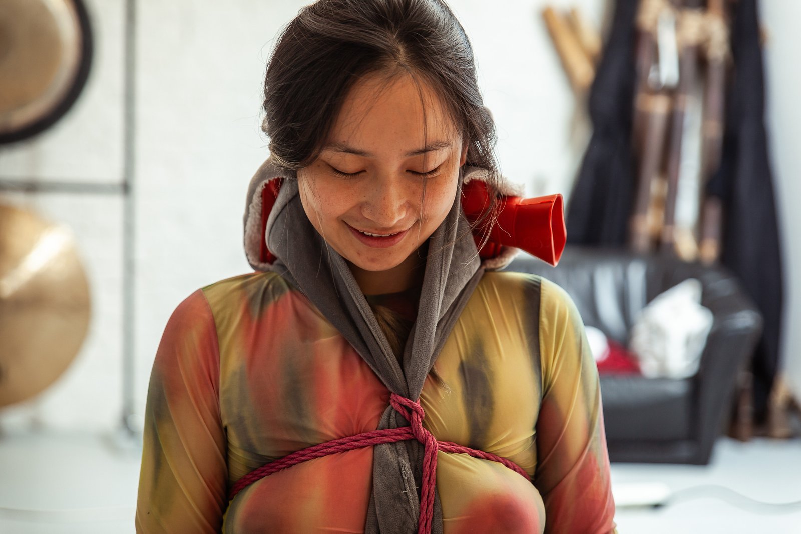 Smiling woman in colorful attire with red rope.
