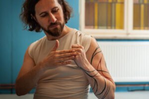 Man with tattoos gestures indoors.