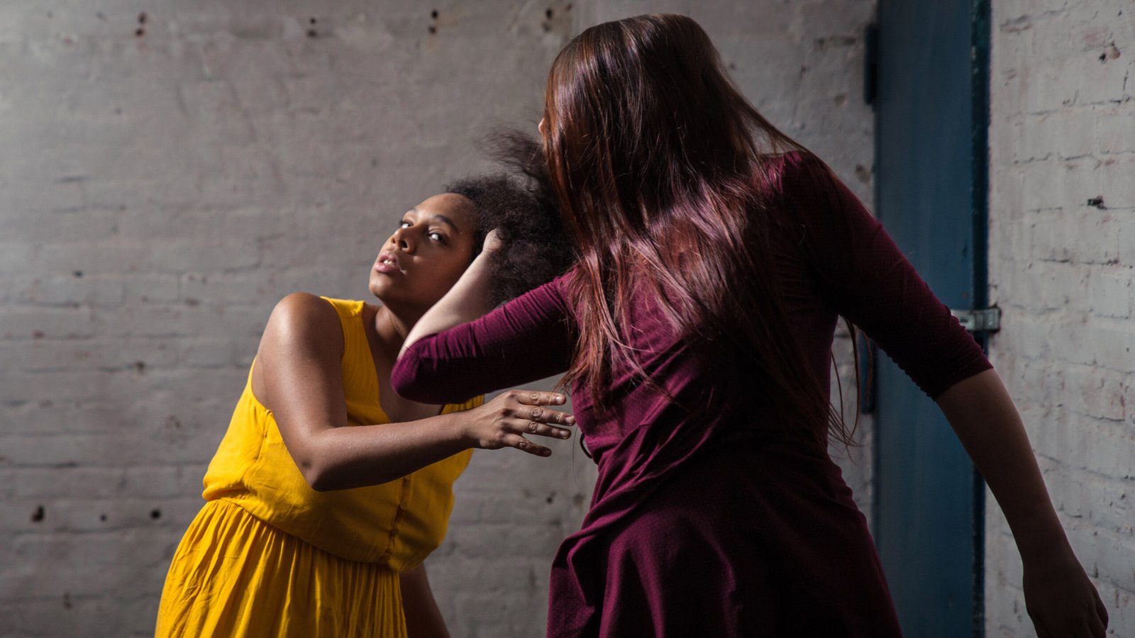 Two women performing expressive contemporary dance indoors.