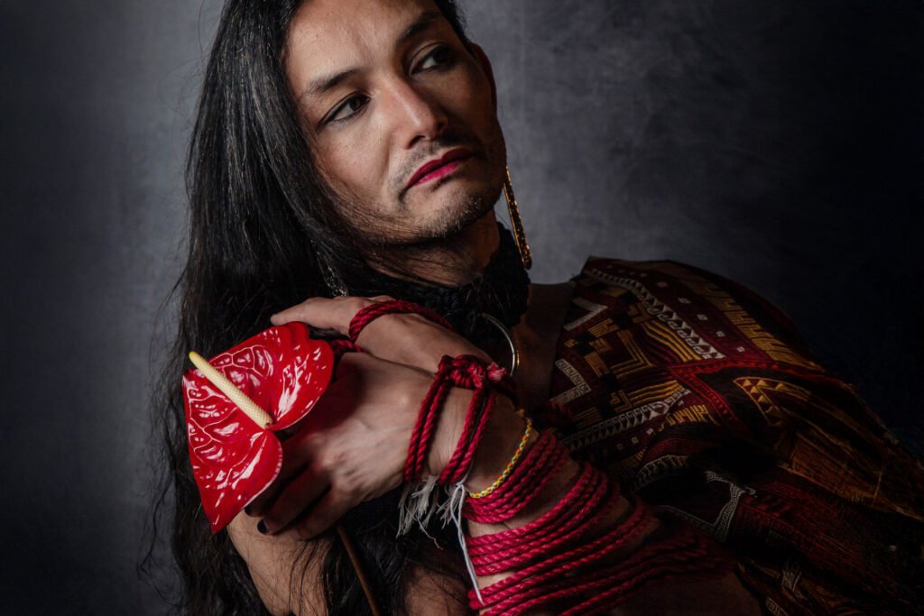 Long-haired person holding red anthurium with bound hands