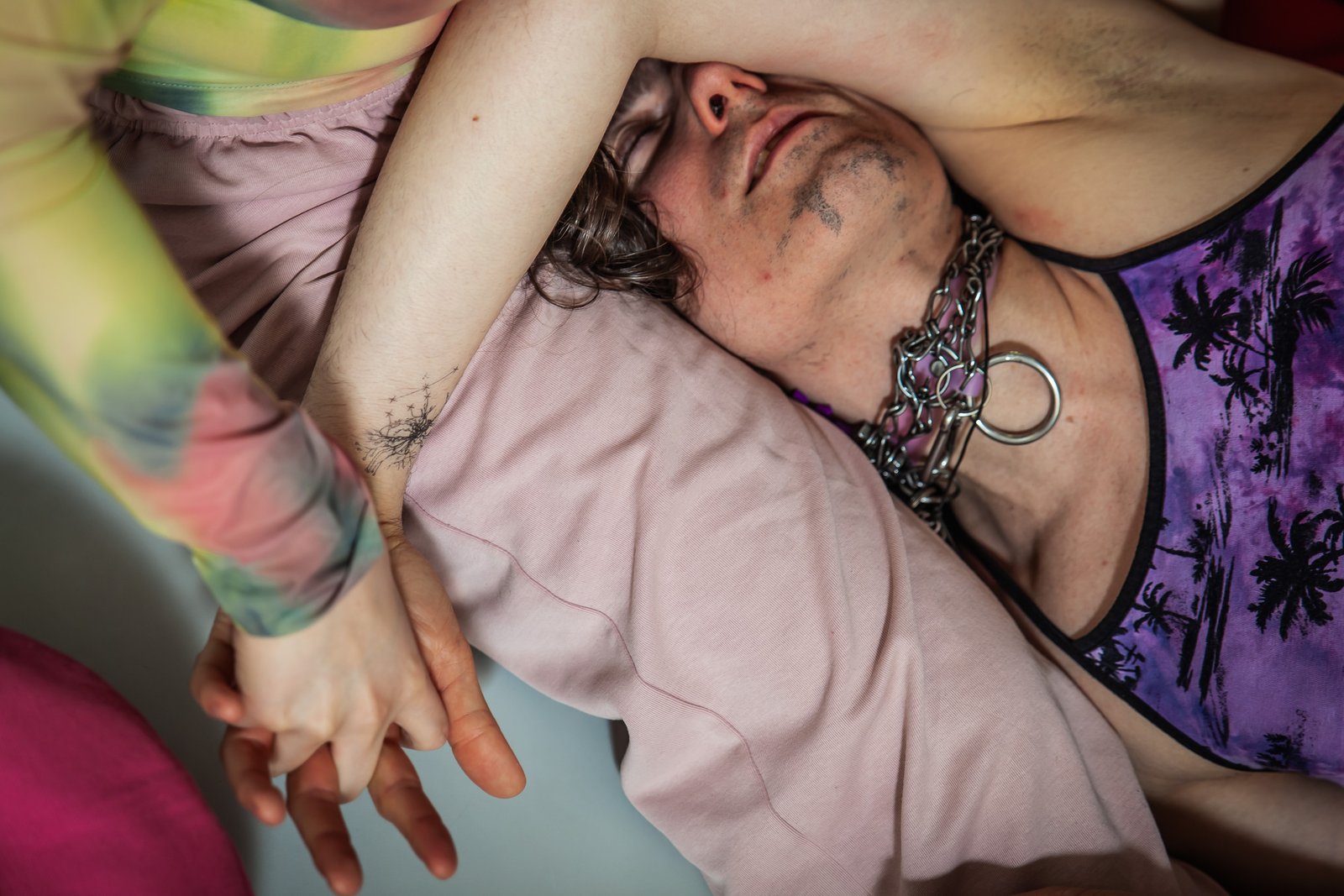 Person lying with intertwined hands and chain necklace