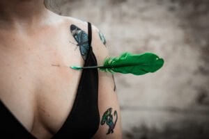 Green feather dart lodged in tattooed shoulder