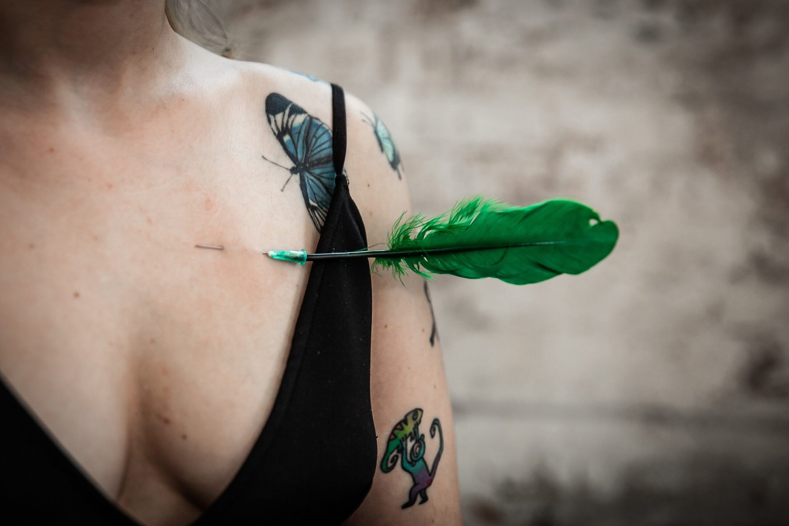 Green feather dart lodged in tattooed shoulder