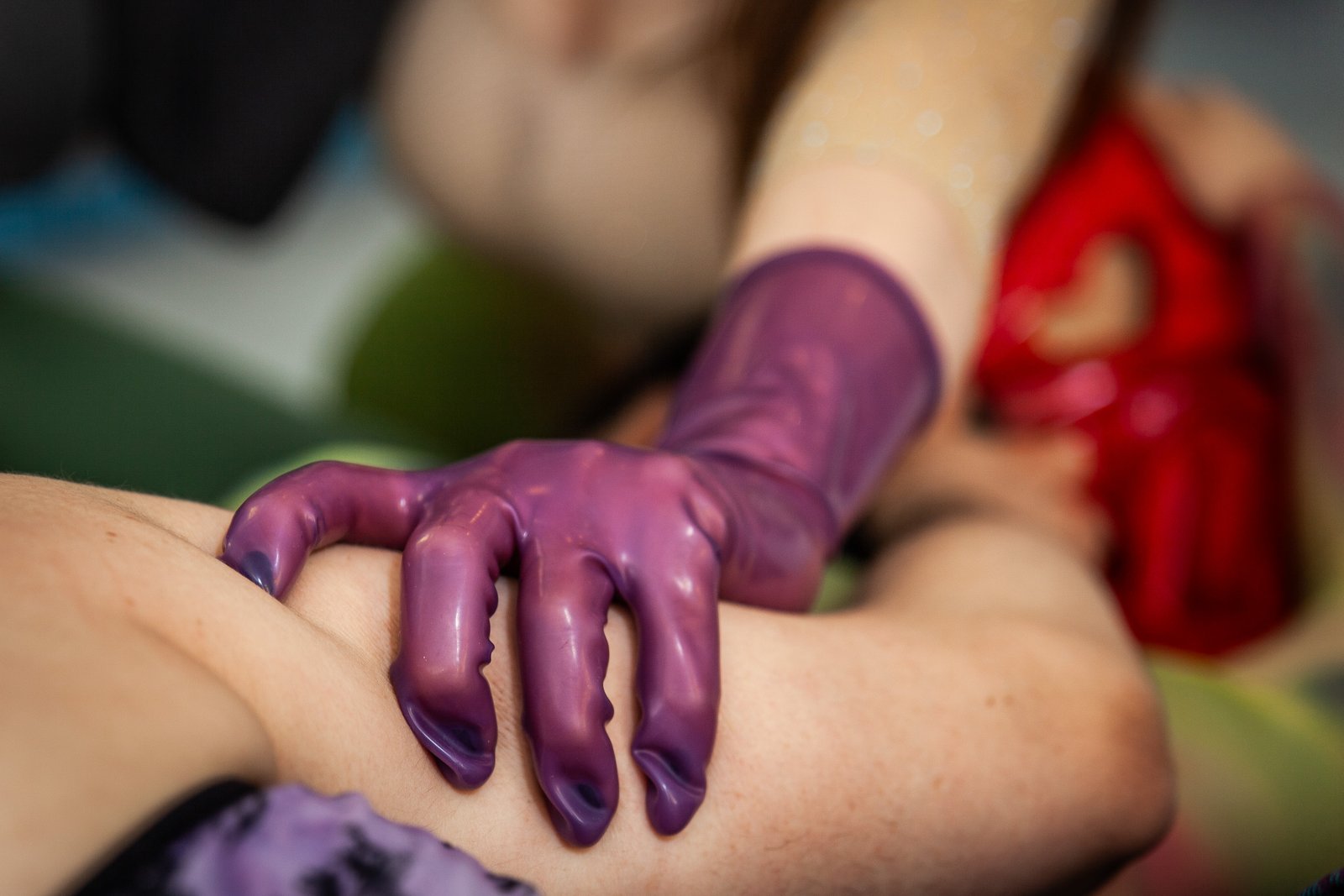 Purple latex-gloved hand gripping a person’s leg