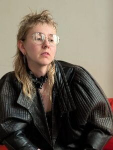 Person in leather jacket sitting on red sofa