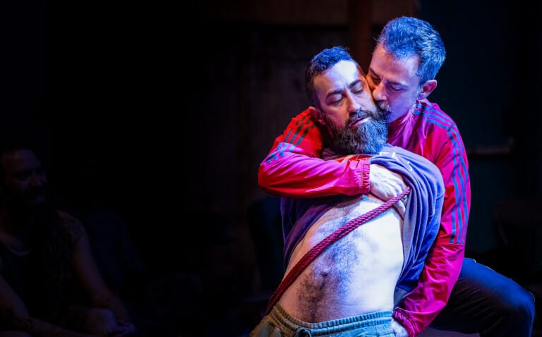 Two men embracing during dramatic stage performance