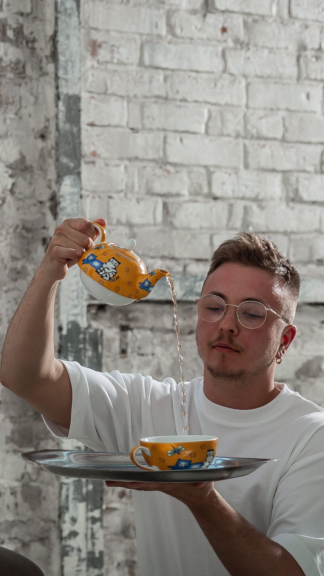 Person serving tea with patterned teapot