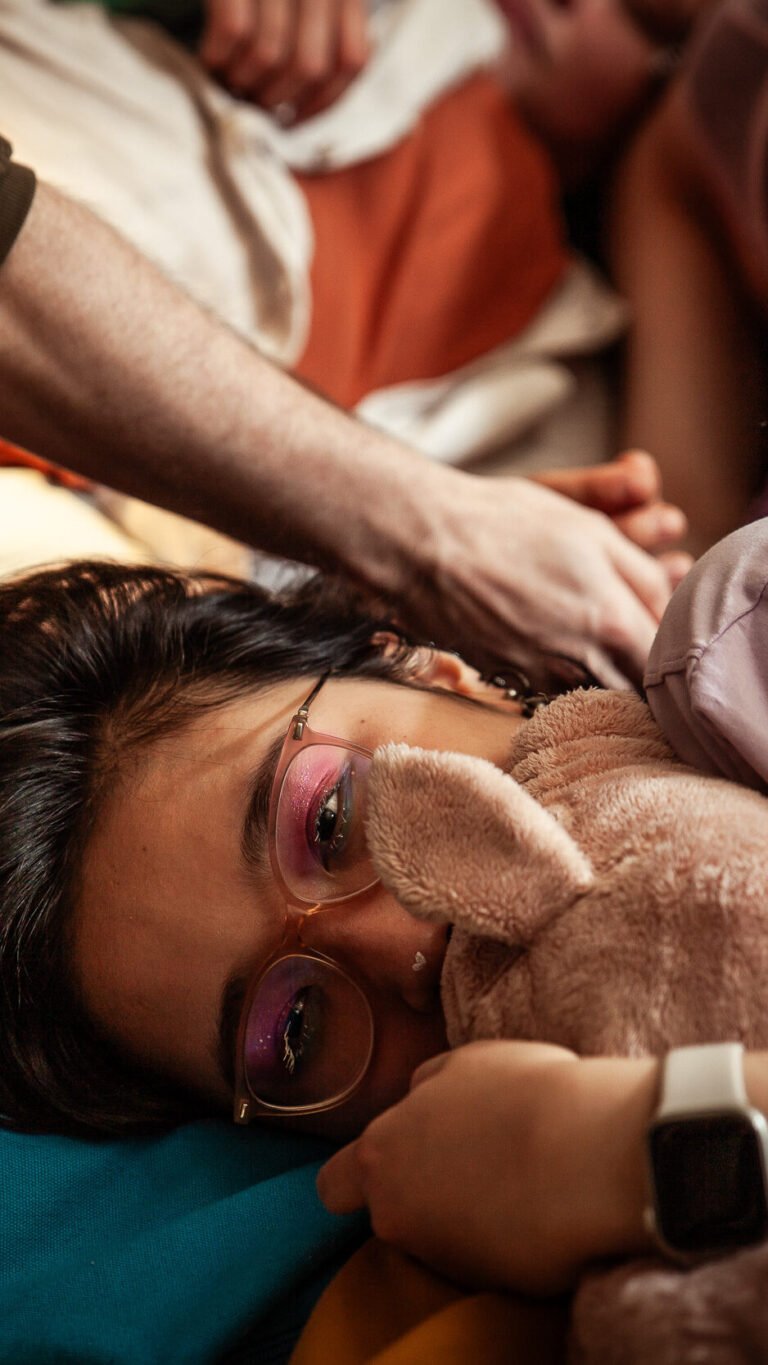 Person resting with teddy bear and glasses.