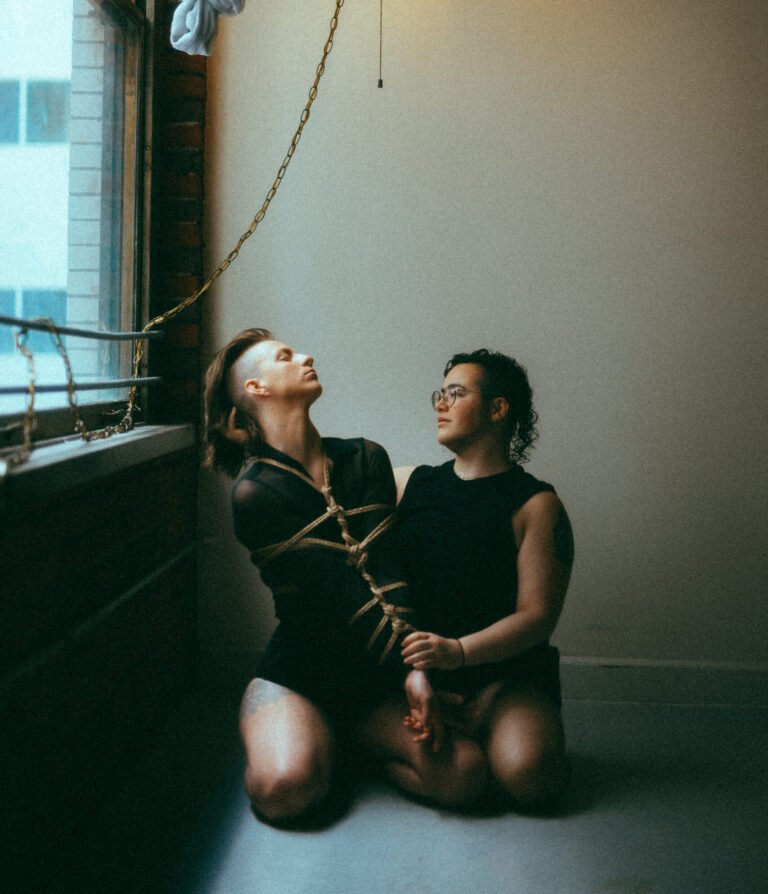 Two people kneeling by window under hanging lamp
